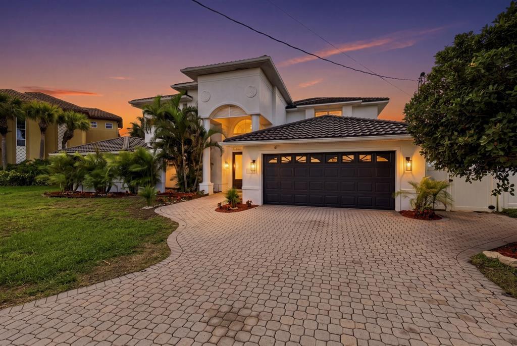 A two-story white house with a dark garage door and a paved driveway at sunset — 461 PALM ISLAND NE, CLEARWATER BEACH, FL