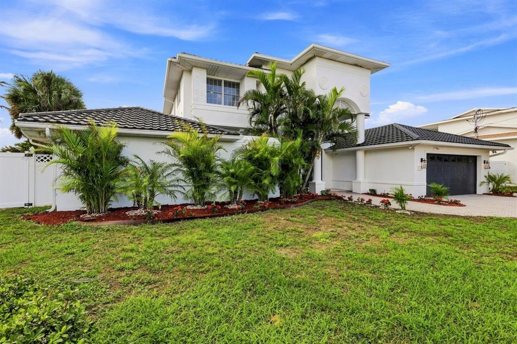 A two-story white house with a dark tiled roof, a garage, and palm tree landscaping — 461 PALM ISLAND NE, CLEARWATER BEACH, FL