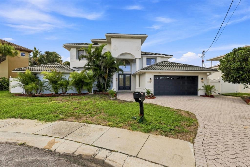 A two-story house with a white exterior, dark garage door, and a paved driveway — 461 PALM ISLAND NE, CLEARWATER BEACH, FL