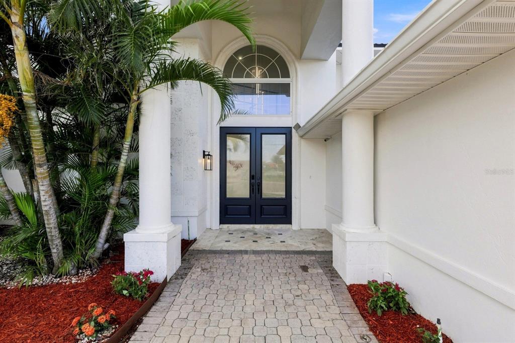 A paved walkway leads to a dark double front door framed by white columns — 461 PALM ISLAND NE, CLEARWATER BEACH, FL
