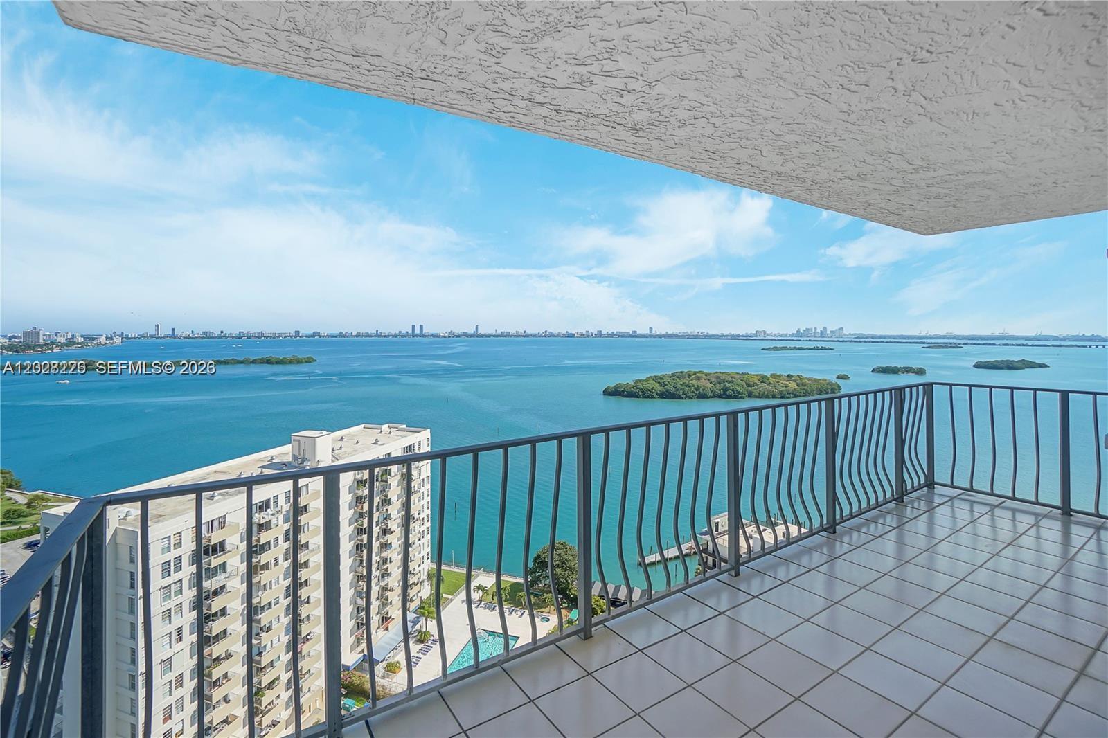 A high-rise balcony overlooks a large body of water with islands and a distant city skyline — 780 NE 69th St # 2302, Miami FL 33138, MIAMI, FL