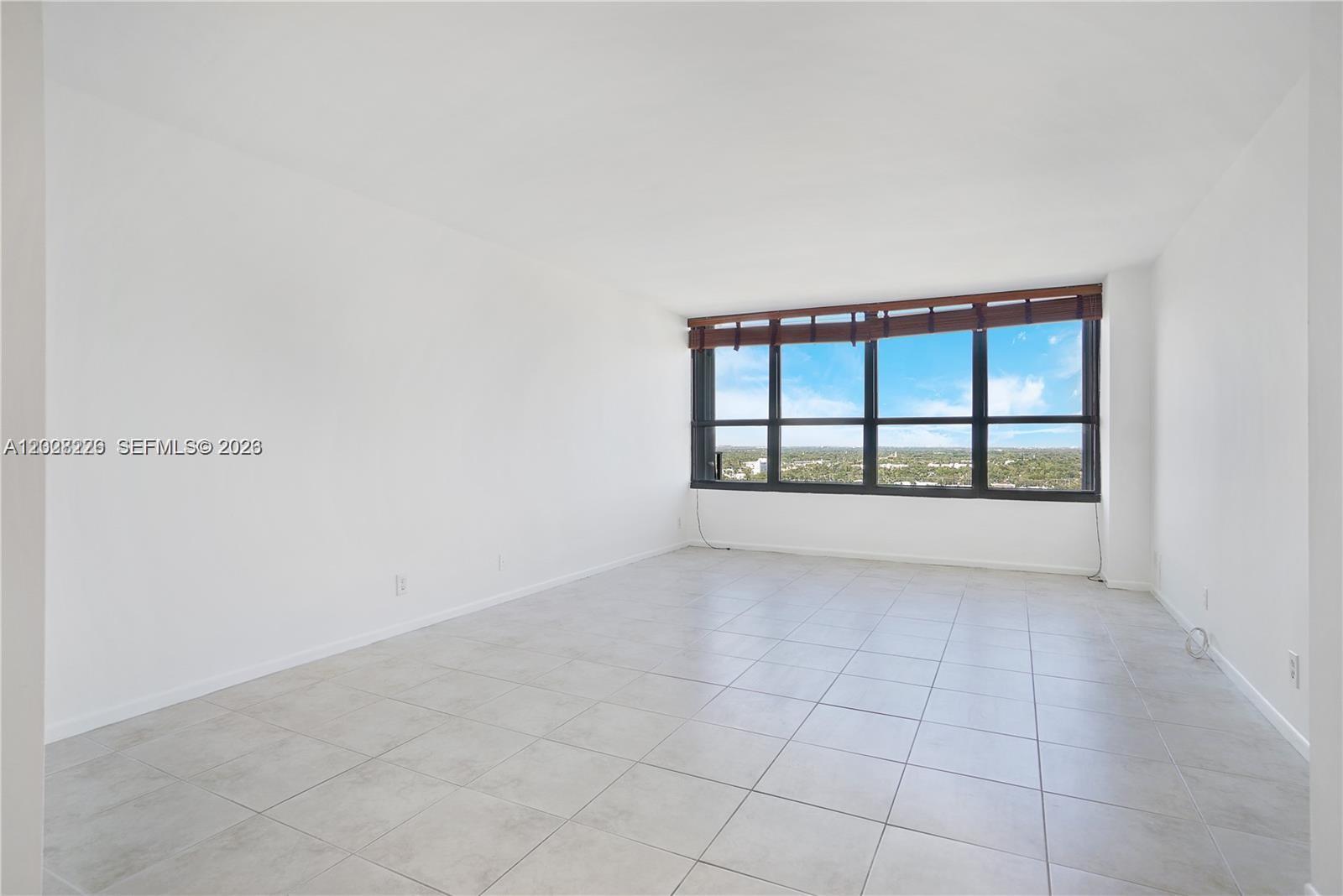 An empty room features white walls, light-colored tile flooring, and a large window with views — 780 NE 69th St # 2302, Miami FL 33138, MIAMI, FL