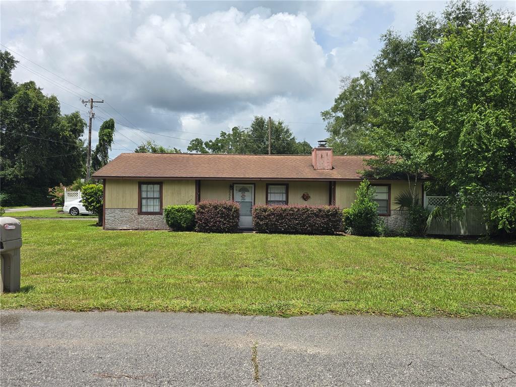 A single-story house with tan siding, stone accents, and a brown roof sits on grass — 5521 NE 4TH PLACE, OCALA, FL