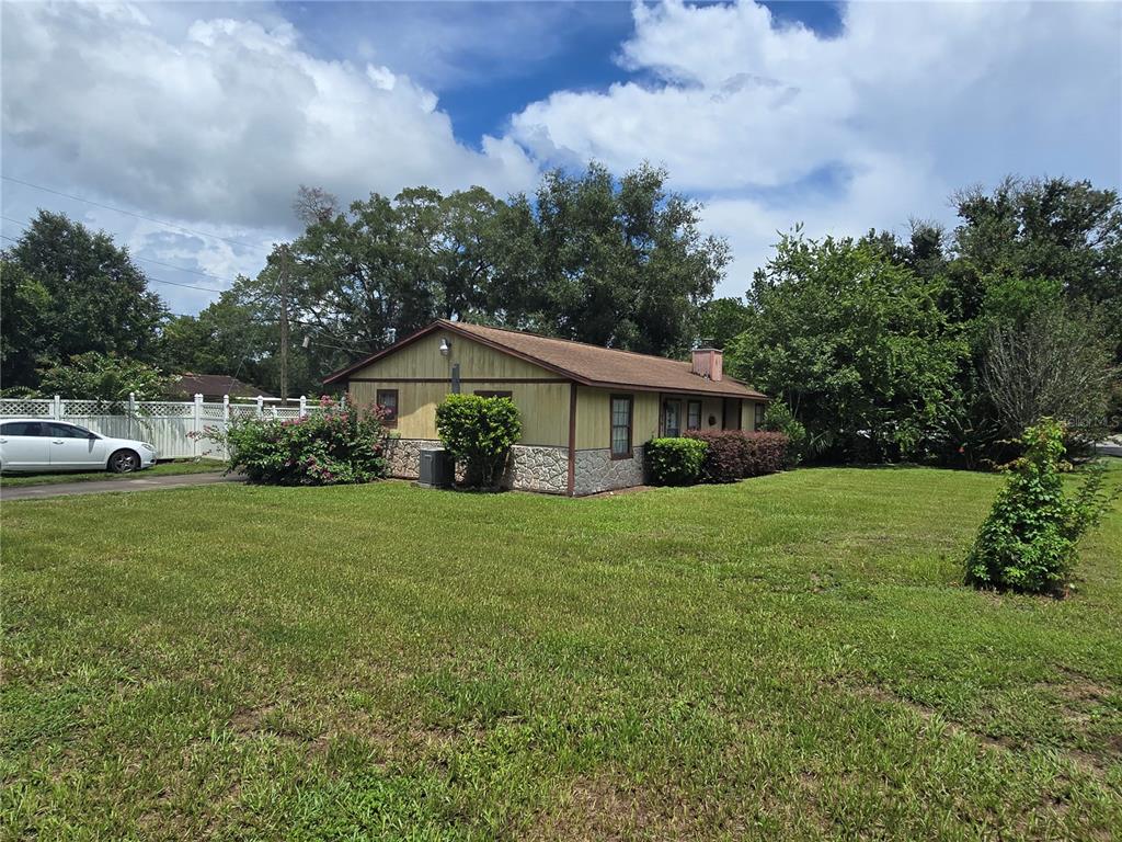 A single-story house with yellow siding and stone accents sits on a grassy lot — 5521 NE 4TH PLACE, OCALA, FL
