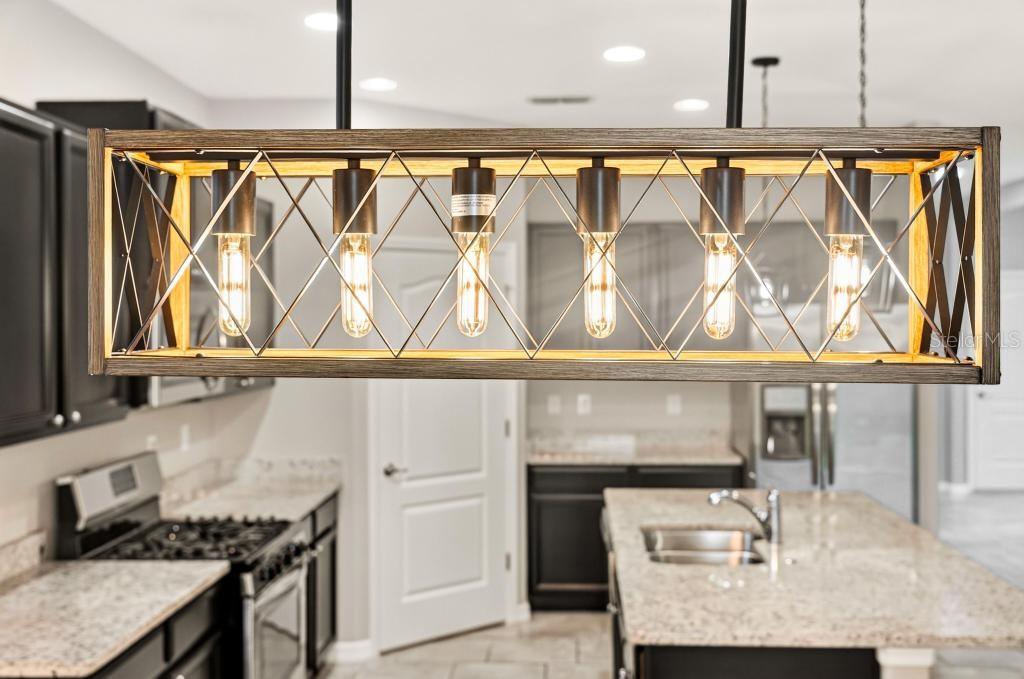 A rectangular wooden pendant light fixture hangs above a kitchen with dark cabinets and countertops — 736 E VICTORIA TRAILS BOULEVARD, DELAND, FL