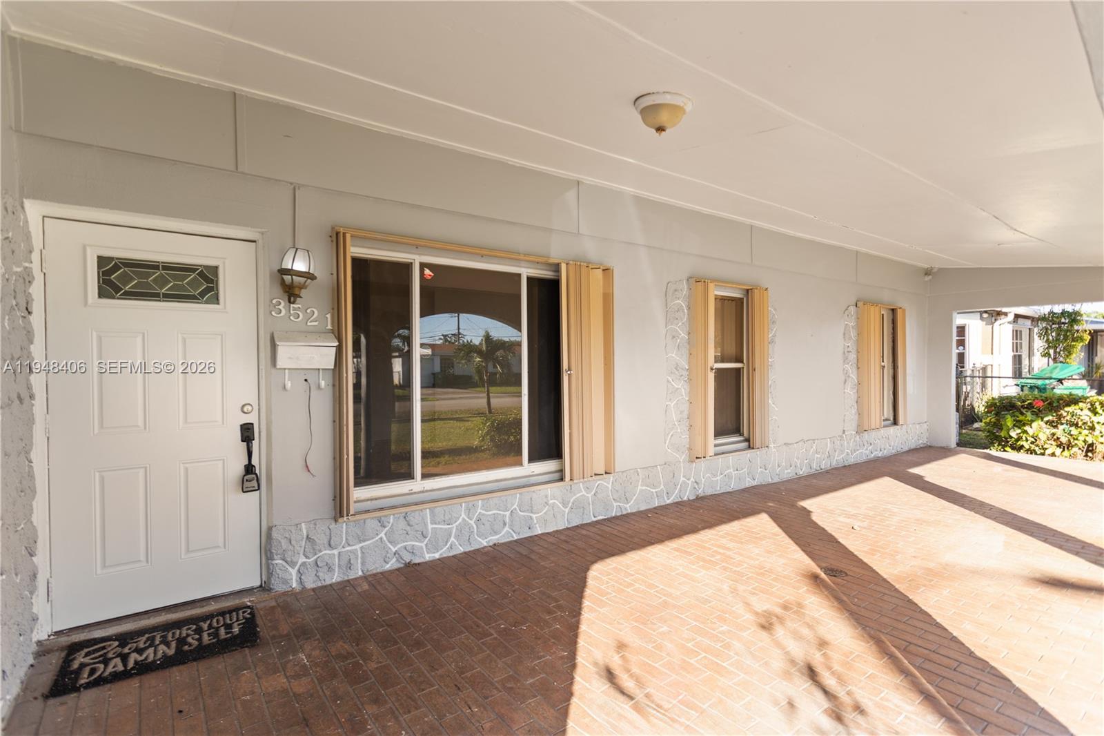 A covered brick patio leads to a front door and windows with accordion shutters — 3521 NW 18th Pl, Lauderhill FL 33311, LAUDERHILL, FL