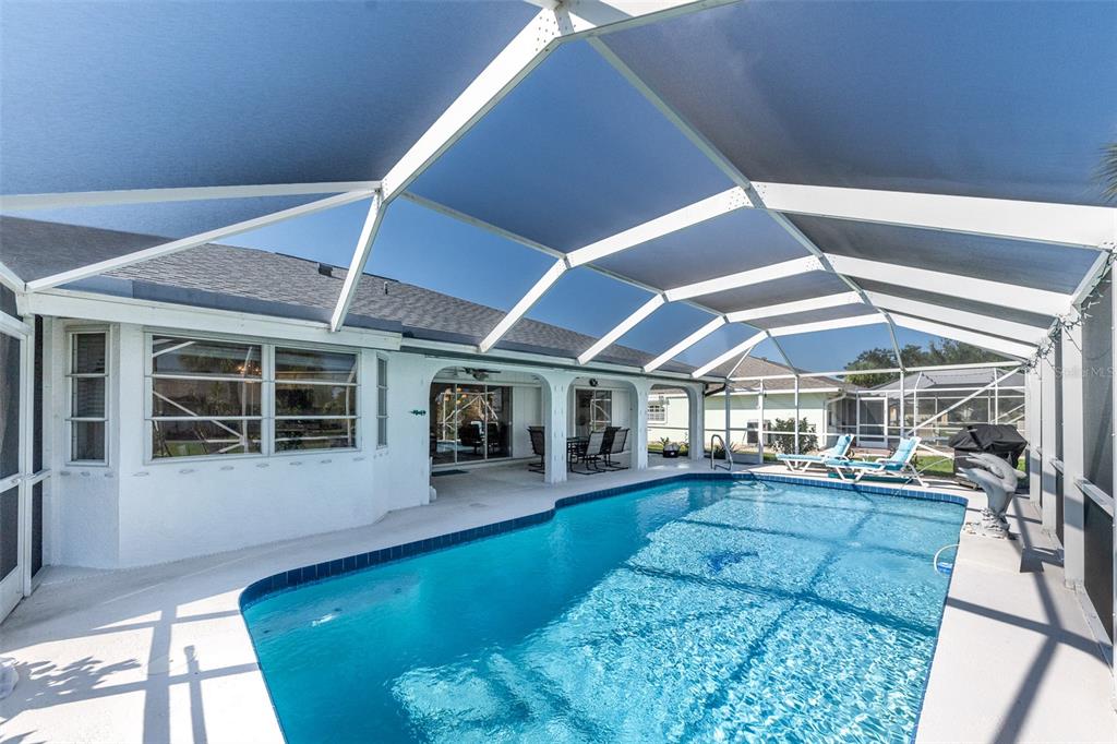 A swimming pool sits on a patio enclosed by a white metal screen cage — 538 W CASHEW, PUNTA GORDA, FL