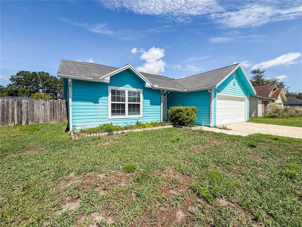 A bright blue single-story house with a white garage door and a grassy front yard — 7966 AMANDAS CROSSING DRIVE E, JACKSONVILLE, FL