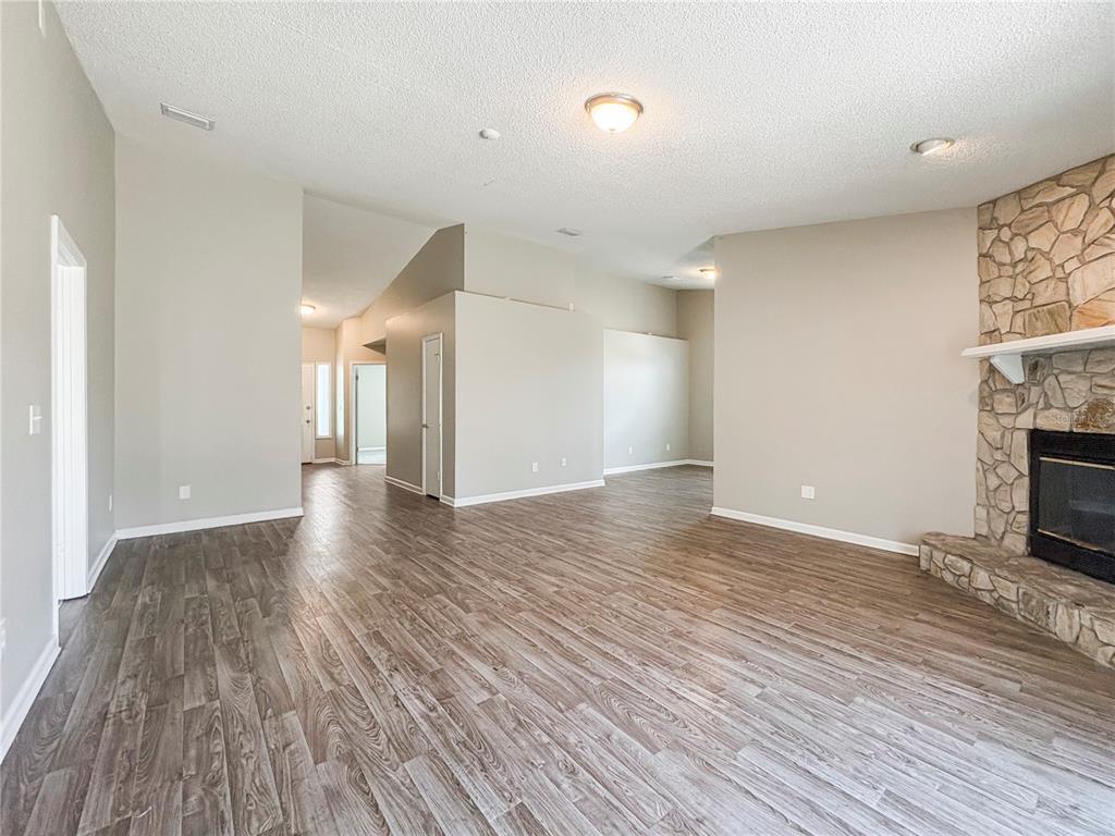 A living room with wood-look flooring, a stone fireplace, and vaulted ceilings — 7966 AMANDAS CROSSING DRIVE E, JACKSONVILLE, FL