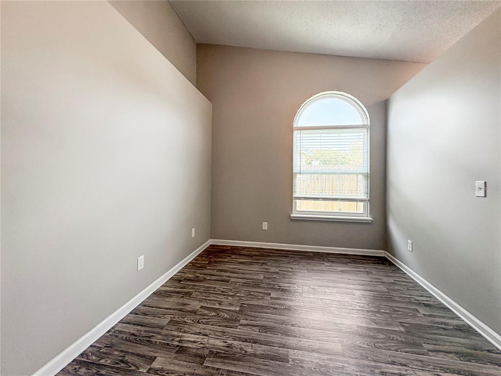 An empty room with gray walls, wood-look flooring, and an arched window — 7966 AMANDAS CROSSING DRIVE E, JACKSONVILLE, FL