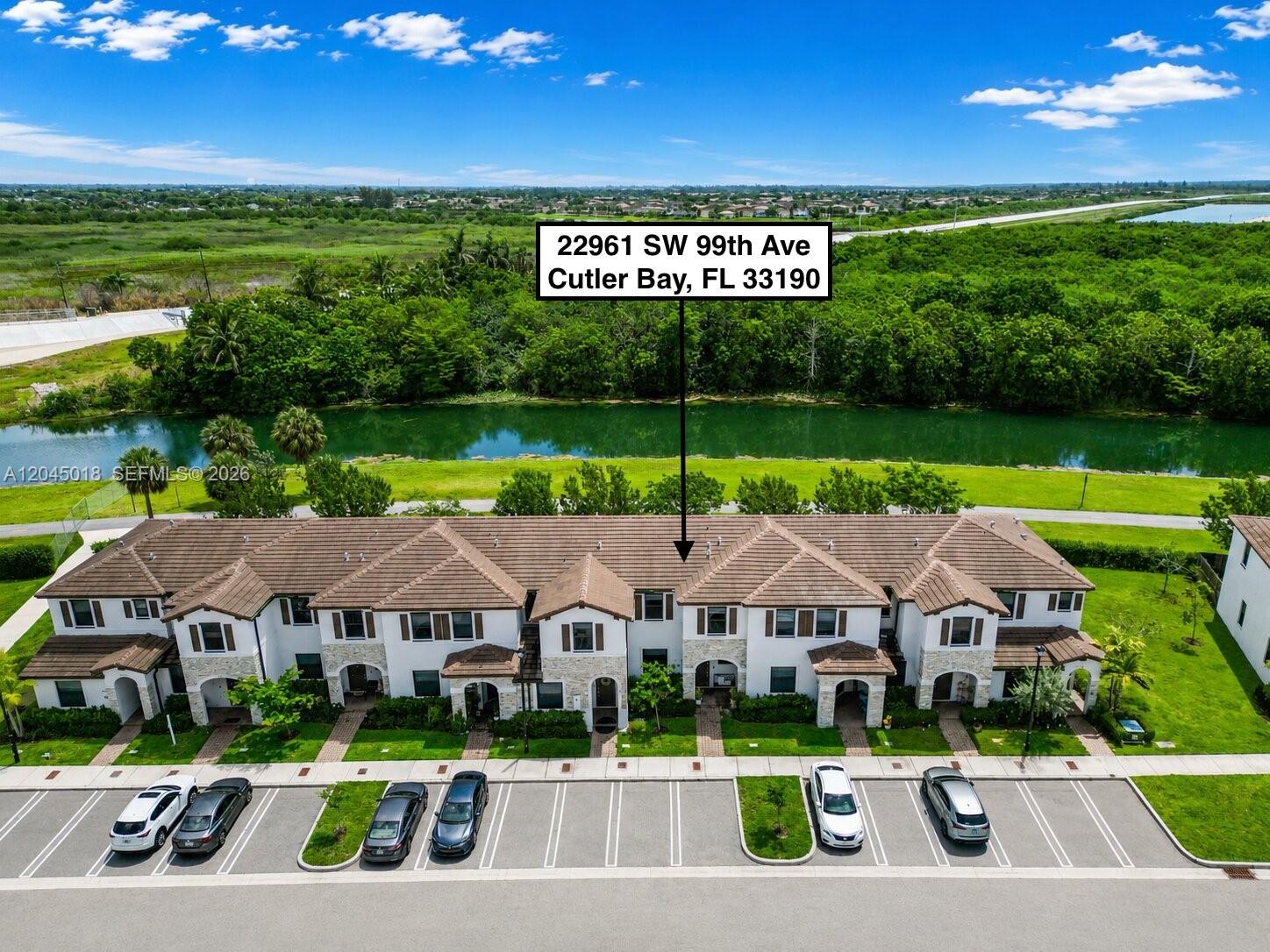 An aerial view shows a multi-unit townhouse complex with a parking lot and canal — 22961 SW 99th Ave, Cutler Bay FL 33190, CUTLER BAY, FL