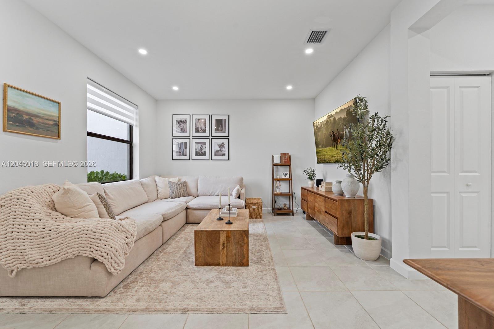 A living room features a beige sectional sofa, a wooden coffee table, and a television — 22961 SW 99th Ave, Cutler Bay FL 33190, CUTLER BAY, FL