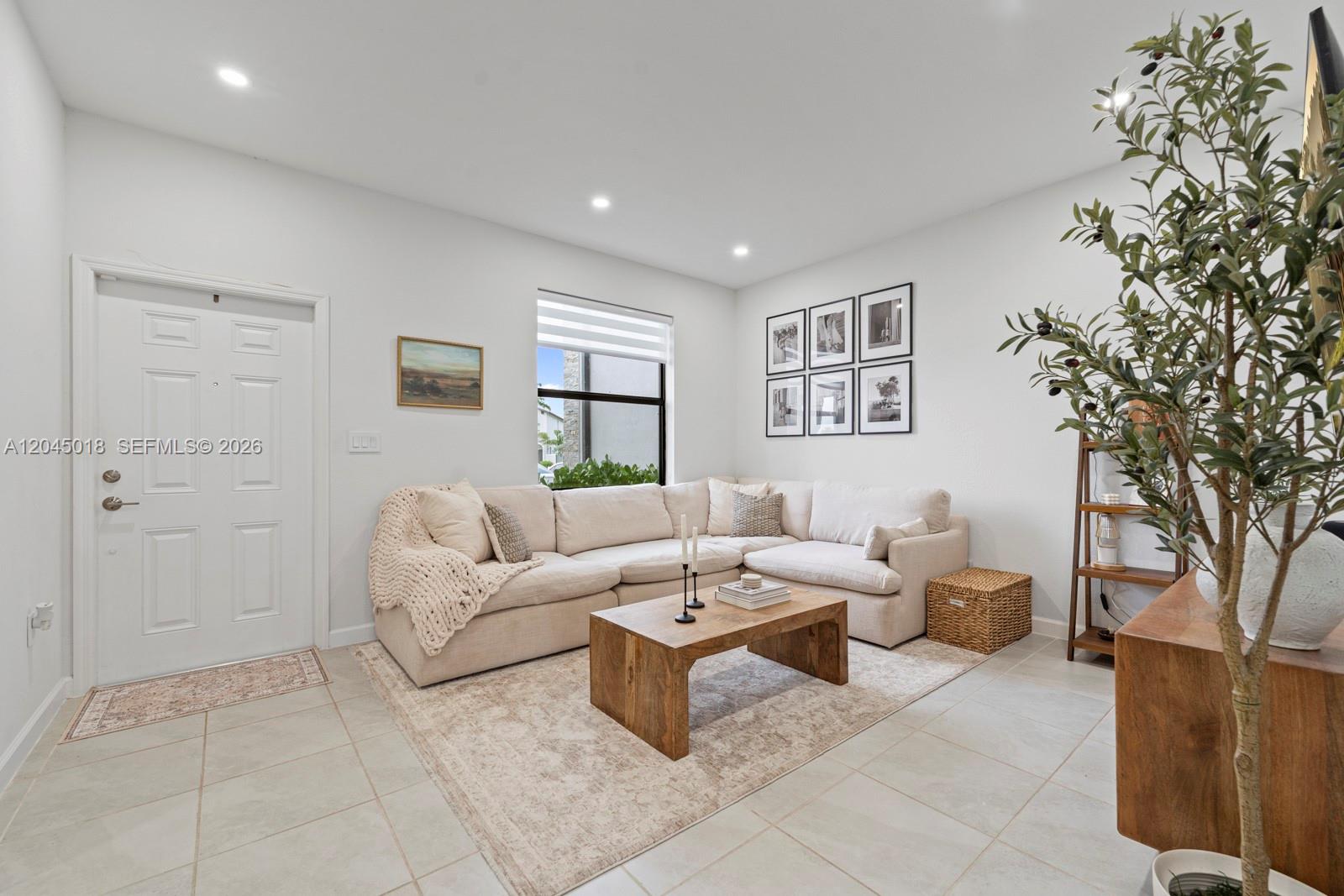 A living room features a beige sectional sofa, a wooden coffee table, and framed wall art — 22961 SW 99th Ave, Cutler Bay FL 33190, CUTLER BAY, FL