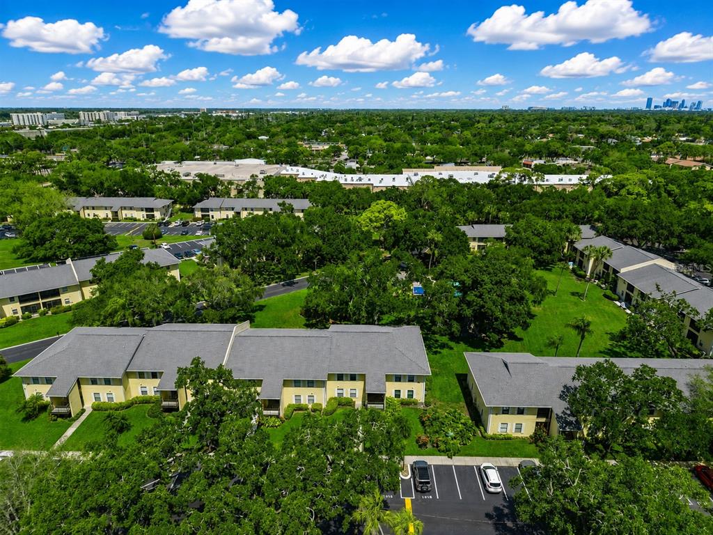 An aerial view shows multi-story apartment buildings surrounded by green trees and parking lots — 3001 58TH AVENUE S UNIT 1014, ST PETERSBURG, FL