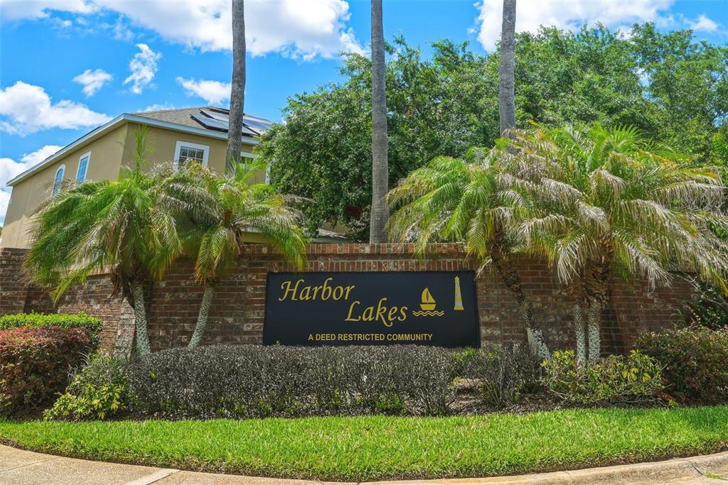 A brick monument sign for Harbor Lakes stands in front of palm trees and houses — 1357 DARNABY WAY, ORLANDO, FL