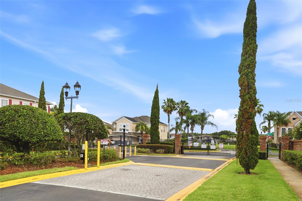 A gated entrance to a residential community features paved roads, landscaping, and tall cypress trees — 1357 DARNABY WAY, ORLANDO, FL
