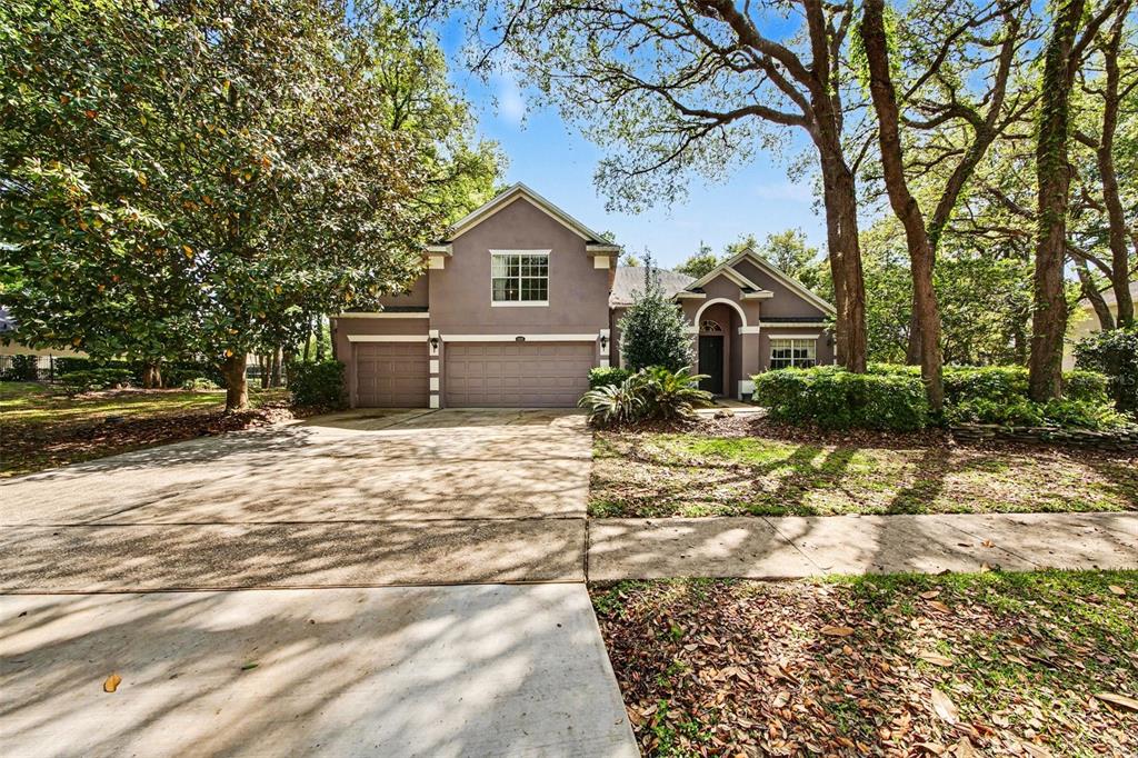 A two-story house with a three-car garage, concrete driveway, and mature trees in the yard — 4323 CALEDONIA AVENUE, APOPKA, FL