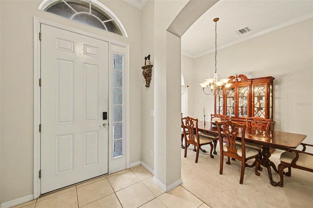 A tiled entryway leads into a formal dining room with a wooden table and hutch — 4323 CALEDONIA AVENUE, APOPKA, FL
