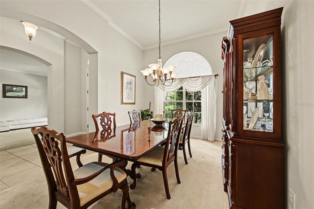 A formal dining room features a wooden table, chairs, a china cabinet, and arched windows — 4323 CALEDONIA AVENUE, APOPKA, FL