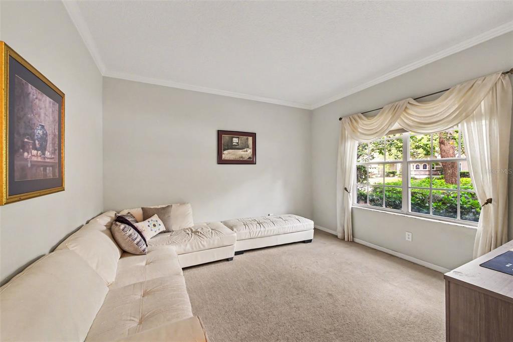 A living room features a beige sectional sofa, carpeted flooring, and a window with curtains — 4323 CALEDONIA AVENUE, APOPKA, FL