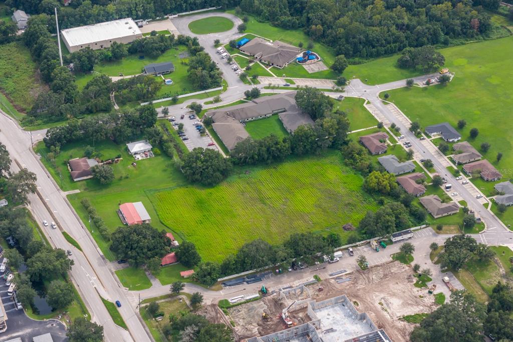 An aerial view shows a large, undeveloped grassy lot surrounded by residential and commercial buildings — 3720 KATHLEEN ROAD, LAKELAND, FL