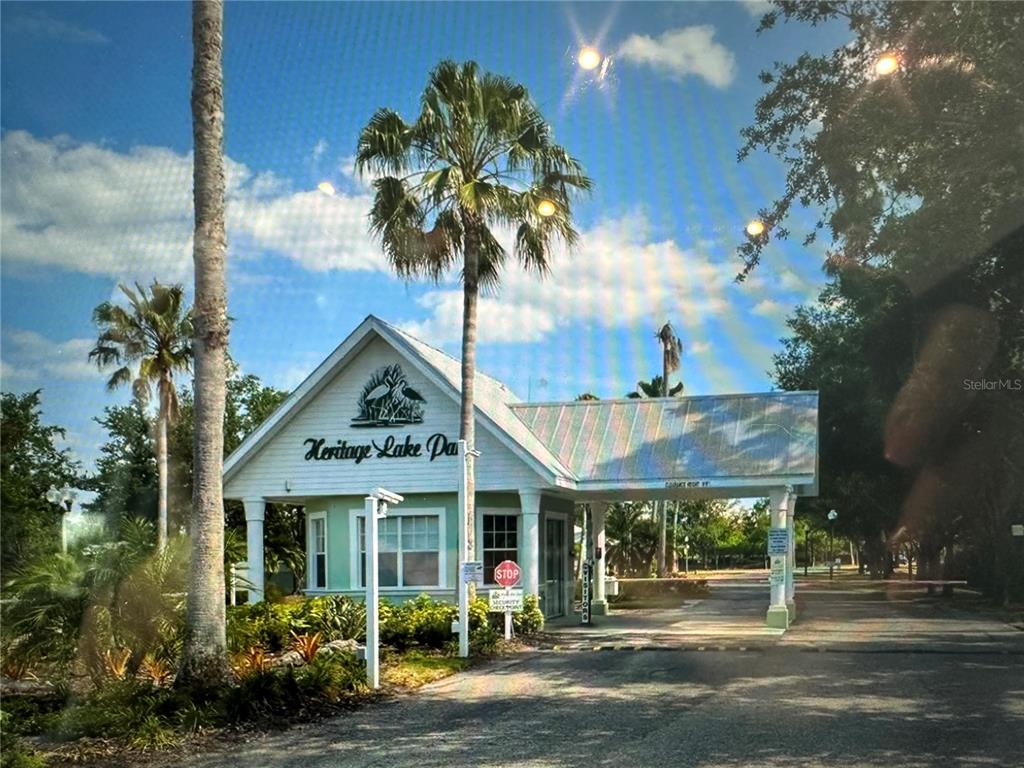 A gated entrance with a white building and palm trees under a blue sky — 2140 HERON LAKE DRIVE UNIT 204, PUNTA GORDA, FL