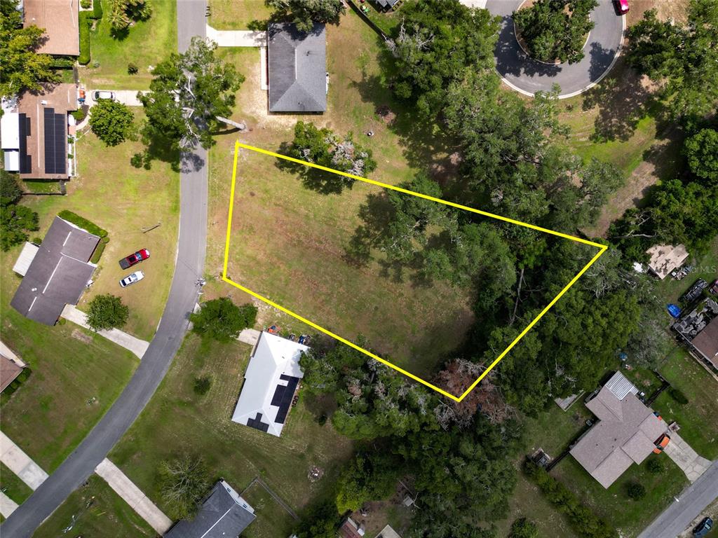 An aerial view shows a vacant, irregularly shaped lot outlined in yellow within a residential neighborhood — TBD SE 54TH AVENUE, BELLEVIEW, FL