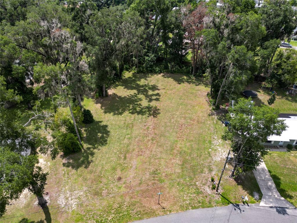 An aerial view shows a vacant, grassy residential lot surrounded by mature trees — TBD SE 54TH AVENUE, BELLEVIEW, FL