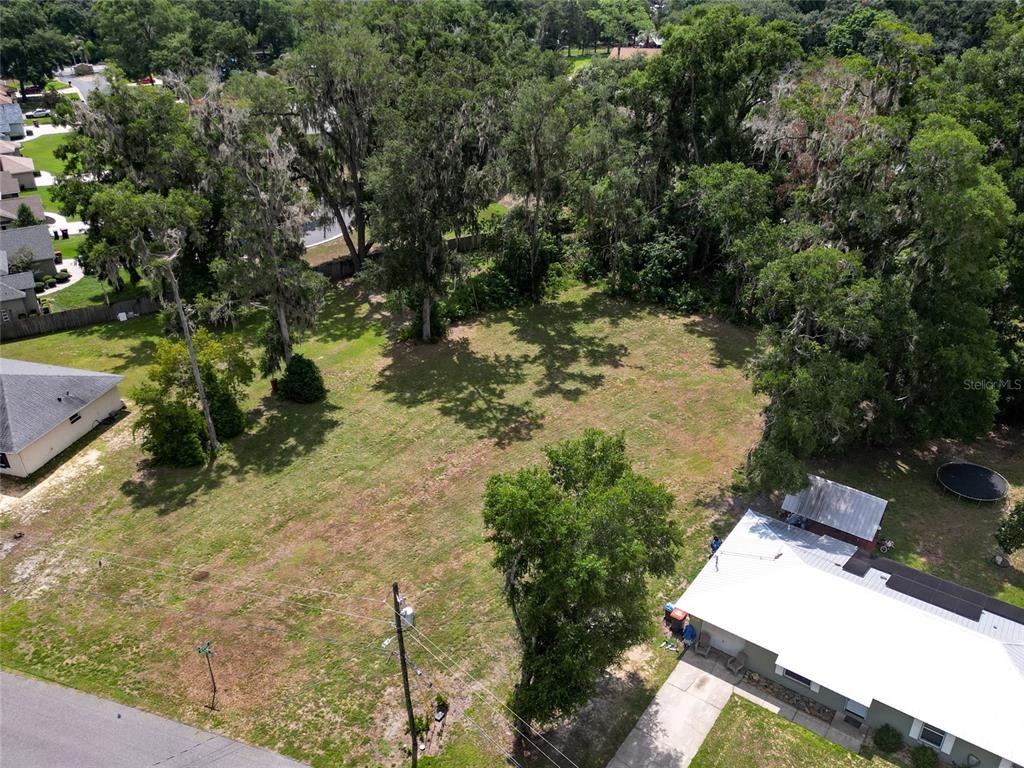 An aerial view shows a vacant grassy lot situated between two residential houses and trees — TBD SE 54TH AVENUE, BELLEVIEW, FL
