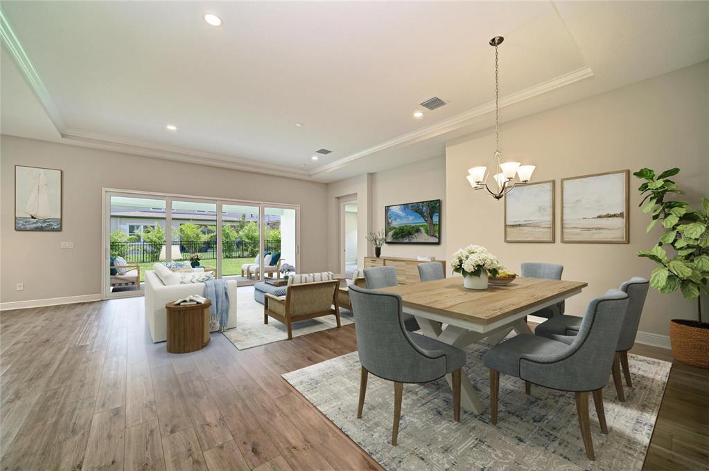 An open-concept living and dining area features wood-look flooring, a tray ceiling, and sliding doors — 5237 WOLF CREEK DRIVE, APOLLO BEACH, FL