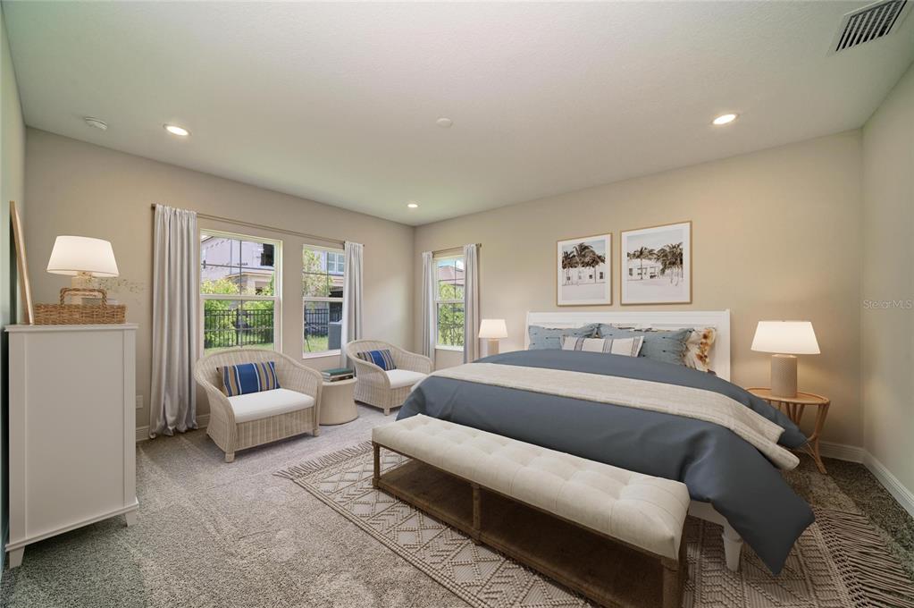 A bedroom features a king bed, two wicker chairs, a bench, and neutral carpeting — 5237 WOLF CREEK DRIVE, APOLLO BEACH, FL
