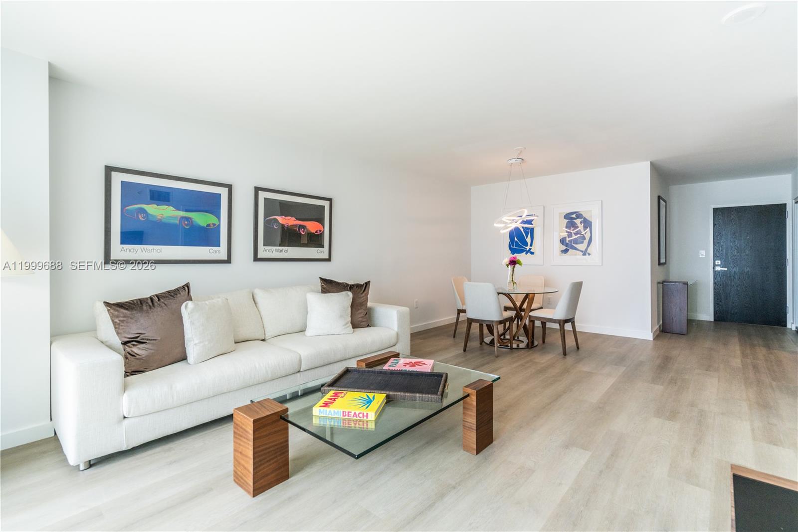 A living and dining area features a white sofa, glass coffee table, and light wood flooring — 90 Alton Rd # 2807, Miami Beach FL 33139, MIAMI BEACH, FL