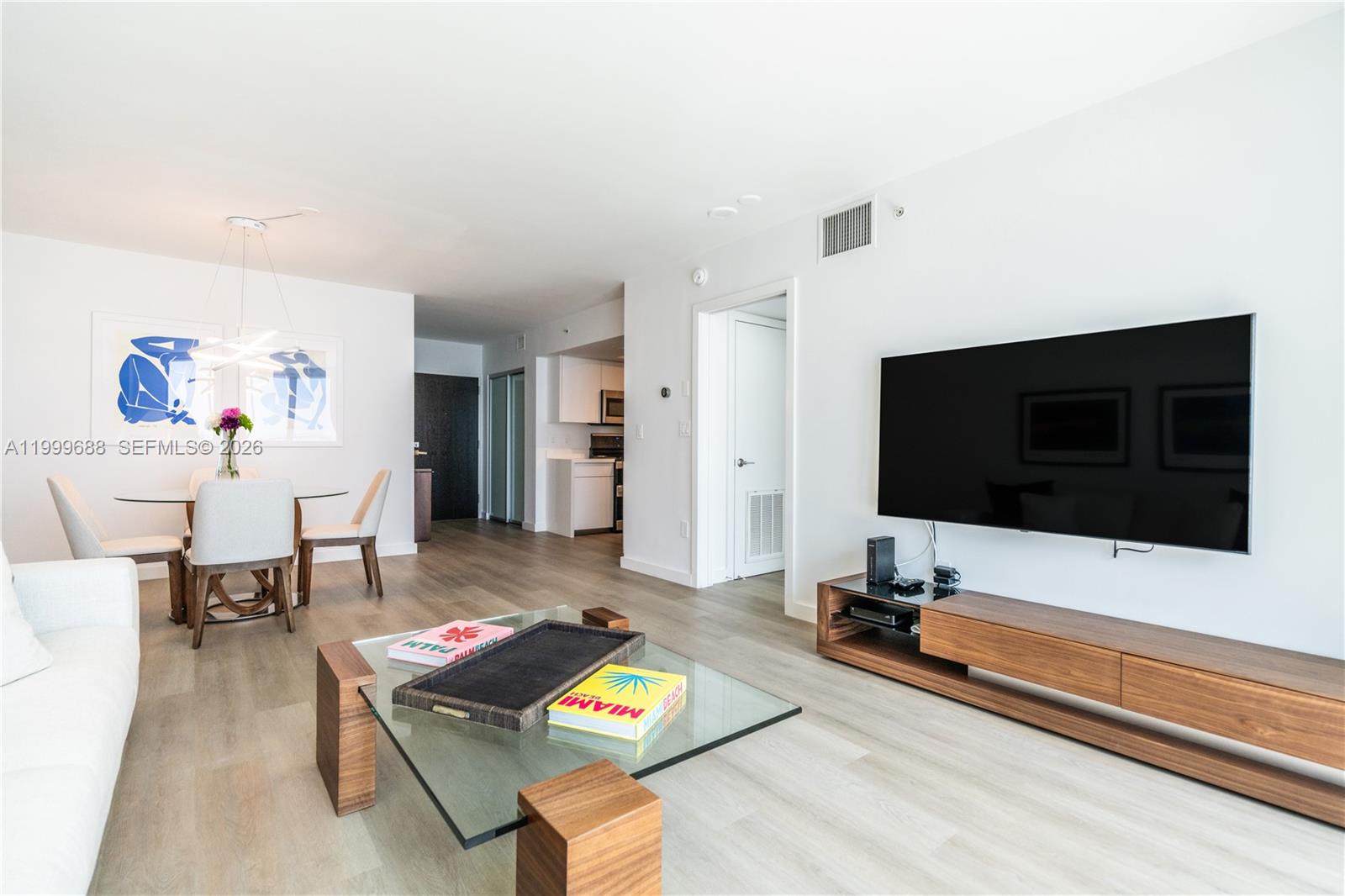 A modern living room features a wall-mounted television, wooden media console, and glass coffee table — 90 Alton Rd # 2807, Miami Beach FL 33139, MIAMI BEACH, FL