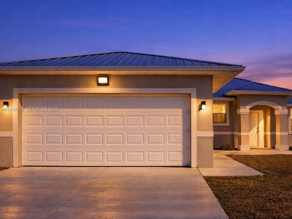 A single-story house exterior features a metal roof, a two-car garage, and a front entrance — 9042 E Broad Circle, La Belle FL 33935, LA BELLE, FL
