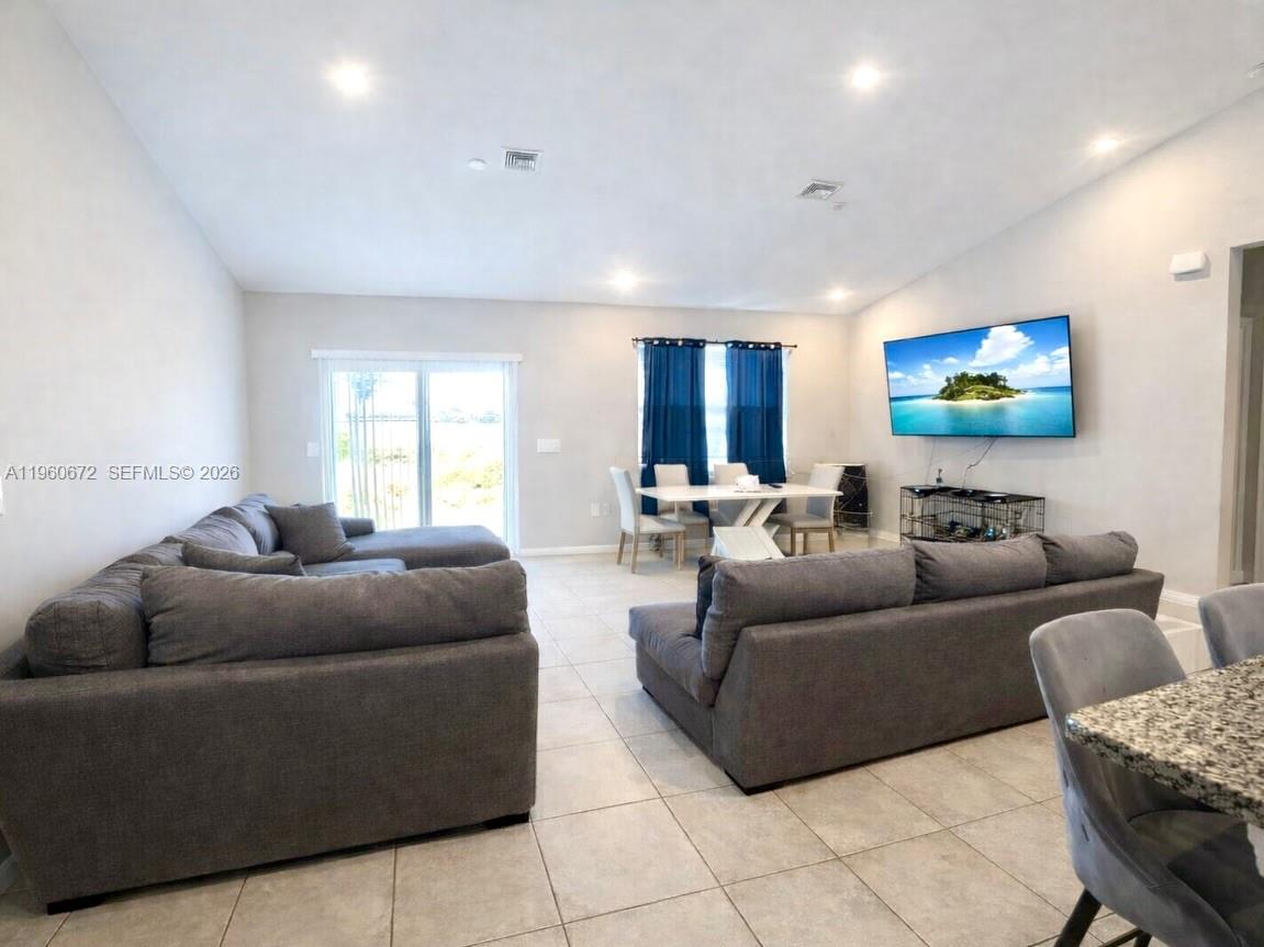 A living room features two gray sectionals, a dining table, and a wall-mounted television — 9042 E Broad Circle, La Belle FL 33935, LA BELLE, FL