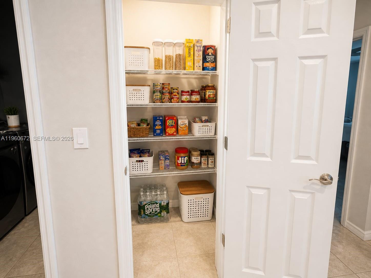 A white pantry closet features wire shelving stocked with various food items and bottled water — 9042 E Broad Circle, La Belle FL 33935, LA BELLE, FL