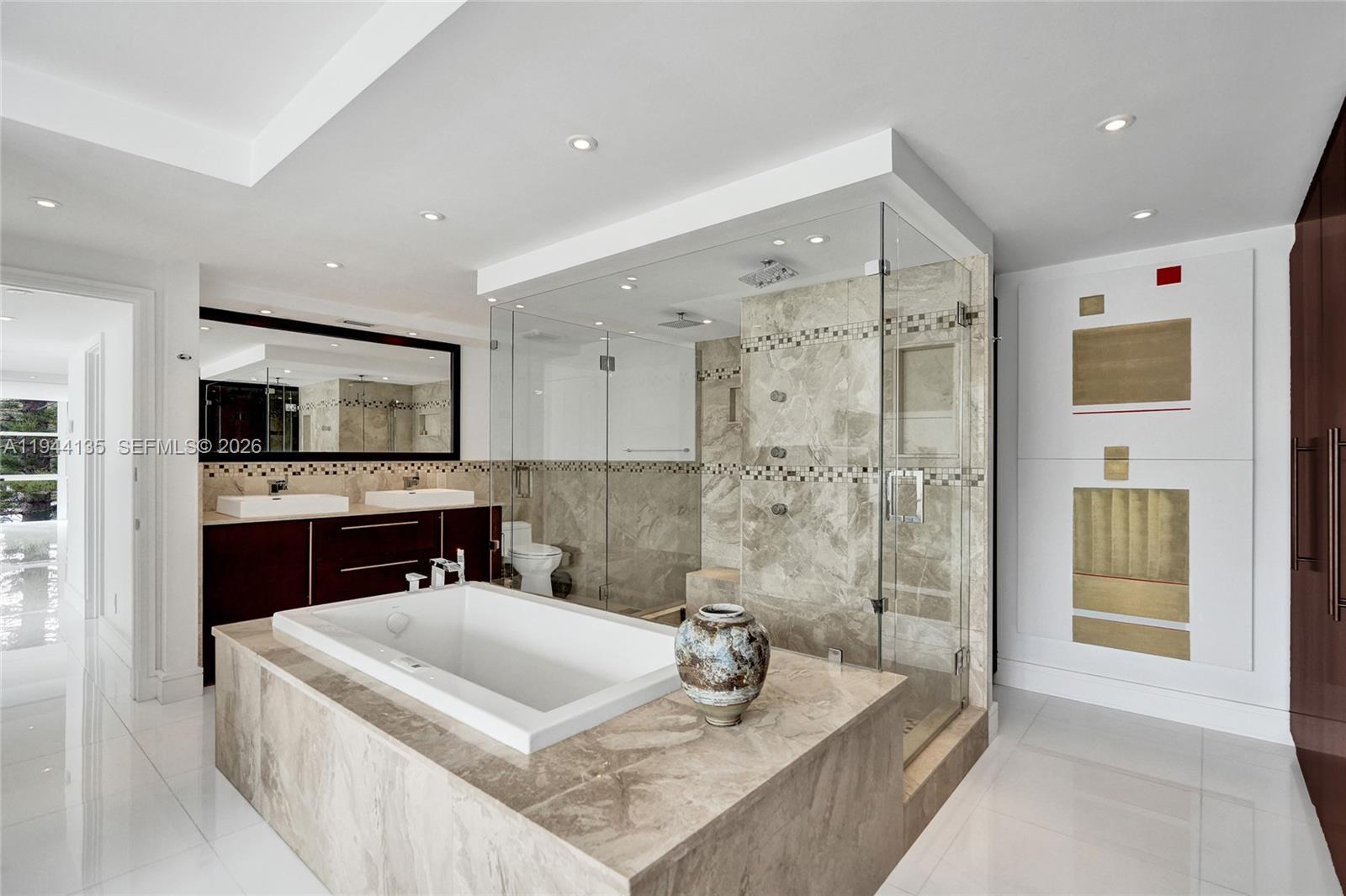 A modern bathroom features a soaking tub, glass-enclosed shower, dual vanity, and marble tile finishes — 1000 Parkview Dr # 330, Hallandale Beach FL 33009, HALLANDALE BEACH, FL