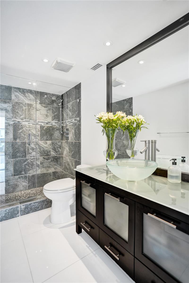 A modern bathroom features a glass vessel sink, dark wood vanity, and a tiled walk-in shower — 1000 Parkview Dr # 330, Hallandale Beach FL 33009, HALLANDALE BEACH, FL