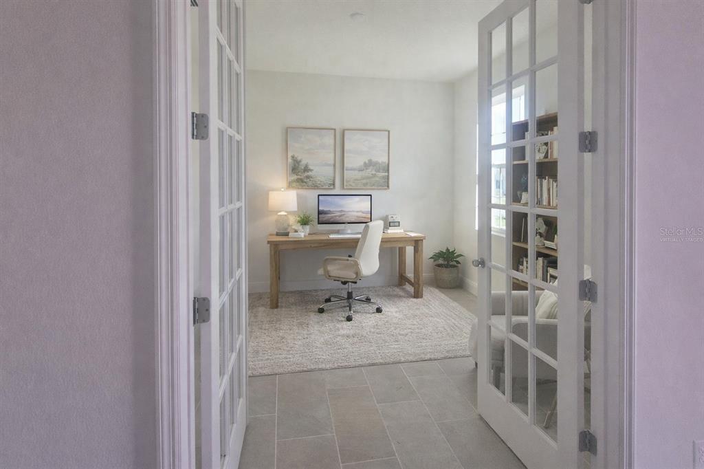 A home office with a wooden desk, white chair, and French doors — 14574 CRESTAVISTA AVENUE, CLERMONT, FL