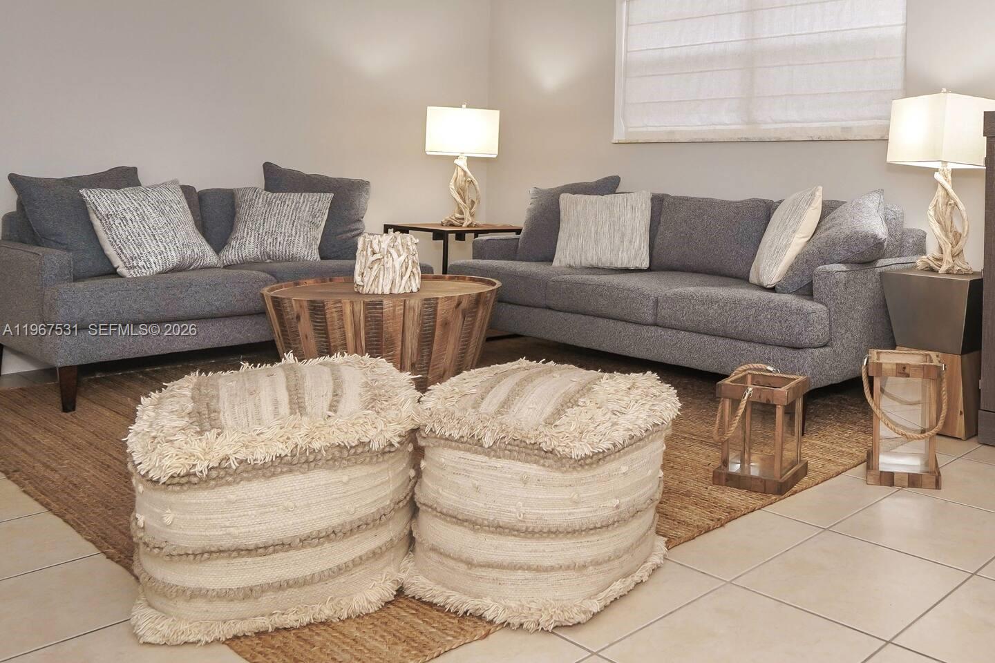 A living room features two gray sofas, a wooden coffee table, and two textured ottomans — 20 SE 12th St, Dania Beach FL 33004, DANIA BEACH, FL