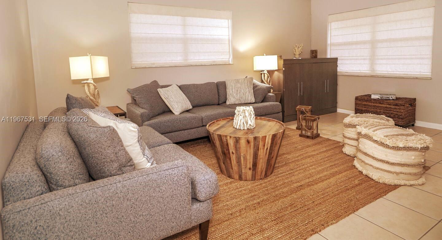 A living room features a gray sectional sofa, a round wooden coffee table, and rugs — 20 SE 12th St, Dania Beach FL 33004, DANIA BEACH, FL