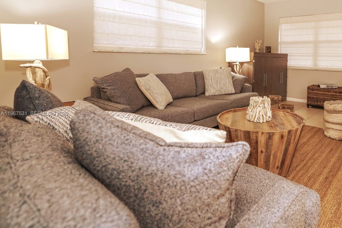 A living room features a gray sofa, a wooden coffee table, and two table lamps — 20 SE 12th St, Dania Beach FL 33004, DANIA BEACH, FL