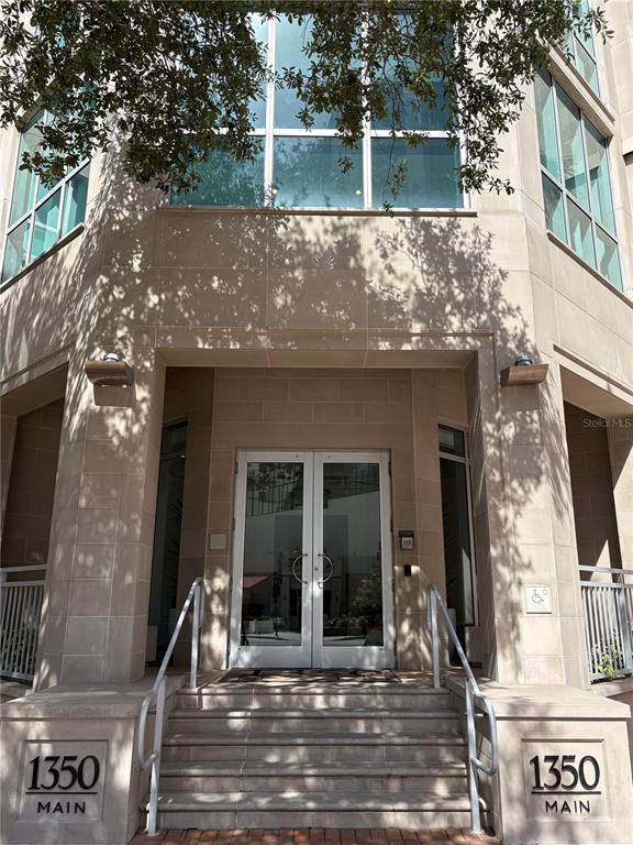 The exterior entrance of a building features stone steps leading to double glass doors — 1350 MAIN STREET UNIT 302, SARASOTA, FL
