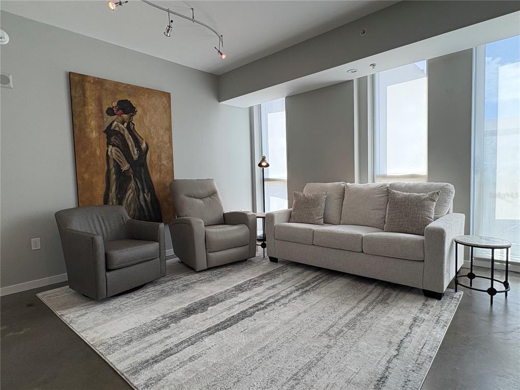 A living room features a sofa, two armchairs, a large painting, and a patterned rug — 1350 MAIN STREET UNIT 302, SARASOTA, FL