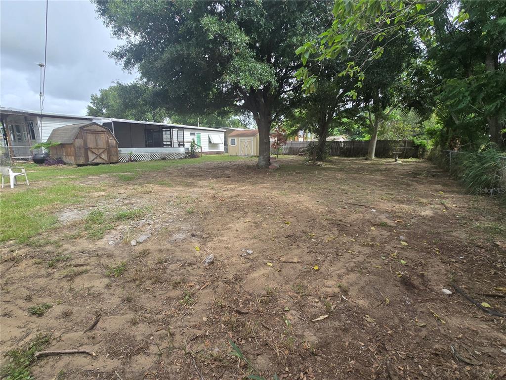 A large, partially dirt backyard features a mobile home, two storage sheds, and mature trees — 29 UNCLE PETE ROAD, HAINES CITY, FL