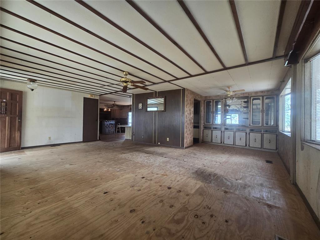 A living room with exposed plywood subflooring, wood-paneled walls, and a beamed ceiling — 29 UNCLE PETE ROAD, HAINES CITY, FL