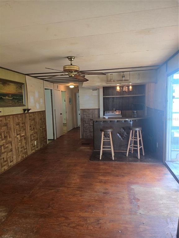 A room with wood-paneled walls, a ceiling fan, and a built-in bar with two stools — 29 UNCLE PETE ROAD, HAINES CITY, FL
