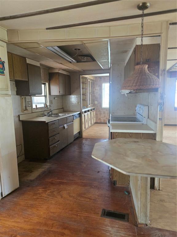 A dated kitchen features wood cabinets, a laminate countertop, and a hanging wicker pendant light — 29 UNCLE PETE ROAD, HAINES CITY, FL