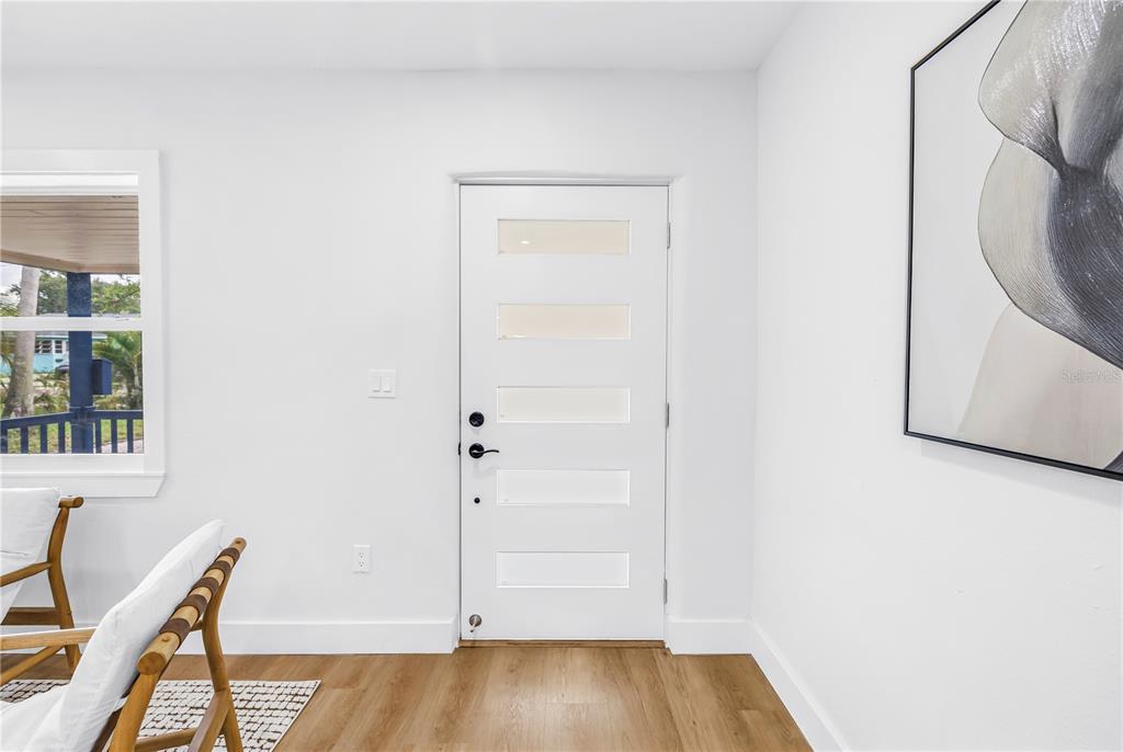 A white front door with five horizontal glass panels sits in a room with wood flooring — 8171 37TH AVENUE N, ST PETERSBURG, FL