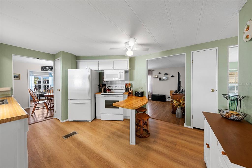 A kitchen with light wood-look flooring, white appliances, and a small wooden breakfast bar — 177 S FIJI CIRCLE, ENGLEWOOD, FL